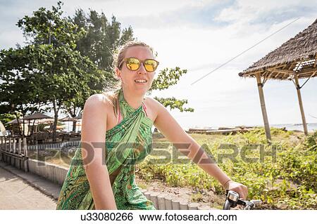 Stock Photograph - Woman cycling near coast, Gili Trawangan, Lombok, Indonesia. Fotosearch