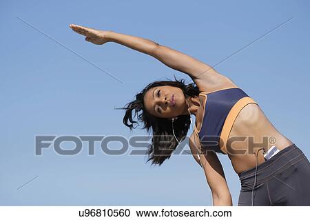 Stock Image - Woman exercising against blue sky. Fotosearch