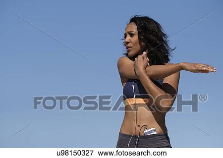 Stock Photo - Woman exercising against blue sky. Fotosearch