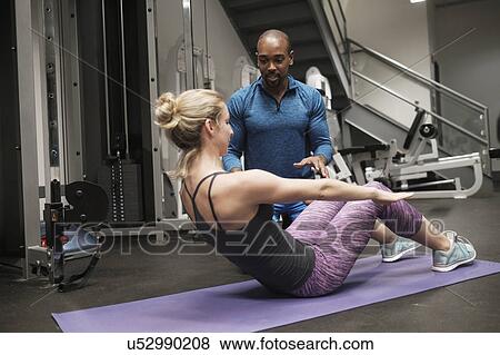 Woman exercising with personal trainer in gym View Large Photo Image Stock Photo - Woman exercising with personal trainer in gym. Fotosearch