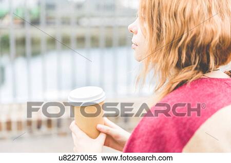 Stock Photography - Woman holding cup looking away, London, UK. Fotosearch
