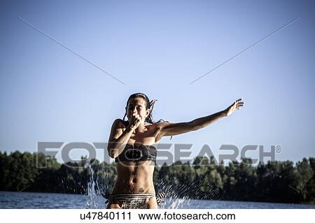 Stock Image - Woman holding nose, jumping in water, Berlin, Germany. Fotosearch