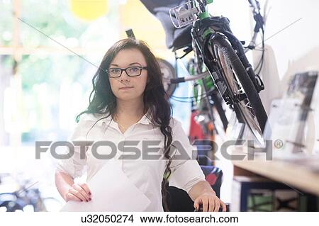 Picture - Woman in bicycle shop holding paperwork. Fotosearch