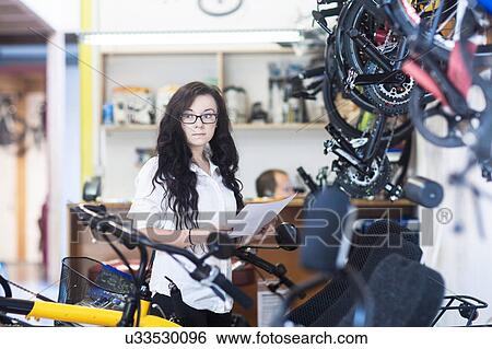 Woman in bicycle shop holding paperwork View Large Photo Image Stock Photograph - Woman in bicycle shop holding paperwork. Fotosearch