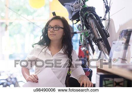 Woman in bicycle shop holding paperwork View Large Photo Image Stock Photograph - Woman in bicycle shop holding paperwork. Fotosearch
