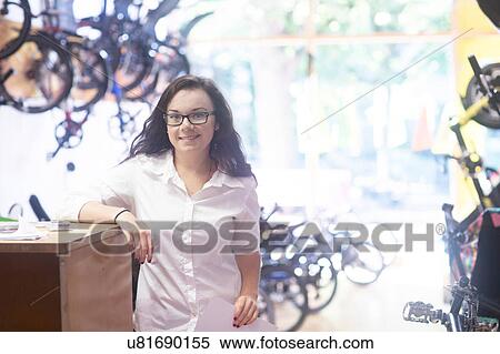 Woman in bicycle shop leaning against counter, looking at camera smiling View Large Photo Image Stock Photography - Woman in bicycle shop leaning against counter, looking at camera smiling. Fotosearch