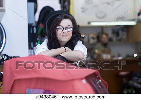 Woman in bicycle shop looking at camera smiling View Large Photo Image Stock Image - Woman in bicycle shop looking at camera smiling. Fotosearch