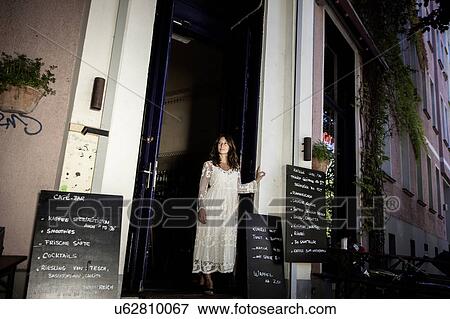 Stock Photo - Woman in cafe doorway looking away, Berlin, Germany. Fotosearch