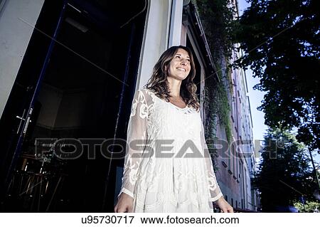 Woman in cafe doorway looking away smiling, Berlin, Germany View Large Photo Image Stock Photo - Woman in cafe doorway looking away smiling, Berlin, Germany. Fotosearch