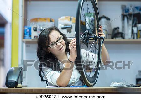 Woman in repair shop looking at bicycle wheel View Large Photo Image Stock Image - Woman in repair shop looking at bicycle wheel. Fotosearch