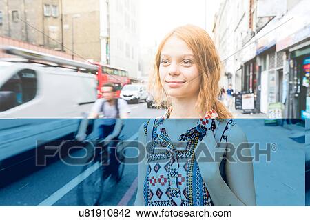 Stock Image - Woman in street looking away smiling, London, UK. Fotosearch