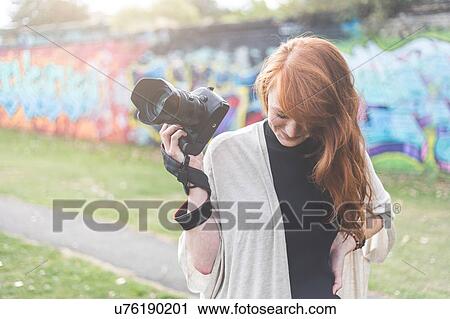Woman in urban area holding camera looking down, London, UK View Large Photo Image Stock Image - Woman in urban area holding camera looking down, London, UK. Fotosearch