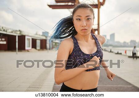 Woman jogging looking at camera, South Bund, Shanghai, China View Large Photo Image Picture - Woman jogging looking at camera, South Bund, Shanghai, China. Fotosearch