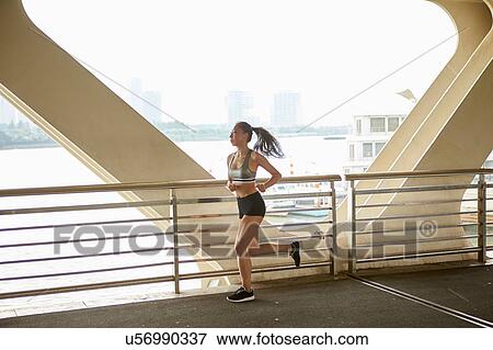 Stock Photo - Woman jogging on elevated walkway, South Bund, Shanghai, China. Fotosearch