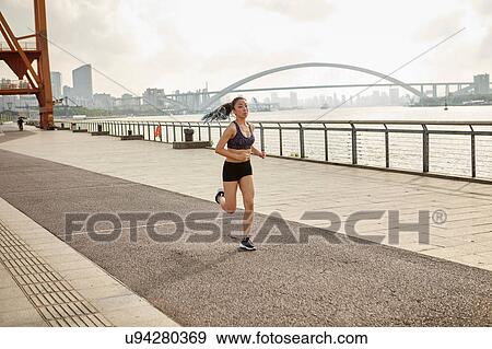 Woman jogging on riverbank in urban area, South Bund, Shanghai, China View Large Photo Image Stock Photo - Woman jogging on riverbank in urban area, South Bund, Shanghai, China. Fotosearch