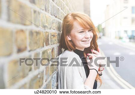 Woman leaning against wall looking away smiling, London, UK View Large Photo Image Stock Image - Woman leaning against wall looking away smiling, London, UK. Fotosearch