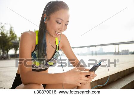 Woman sitting on steps using smartphone View Large Photo Image Stock Photograph - Woman sitting on steps using smartphone. Fotosearch