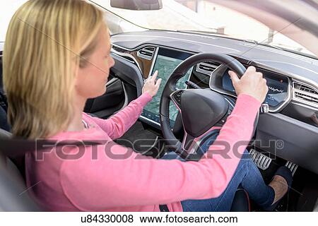 Woman using satellite navigation system in electric car View Large Photo Image Stock Photo - Woman using satellite navigation system in electric car. Fotosearch