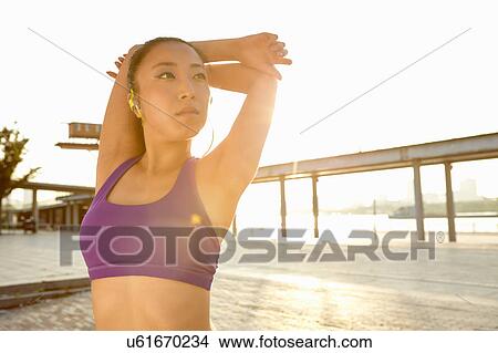 Woman wearing crop top hand behind head, looking away View Large Photo Image Picture - Woman wearing crop top hand behind head, looking away. Fotosearch