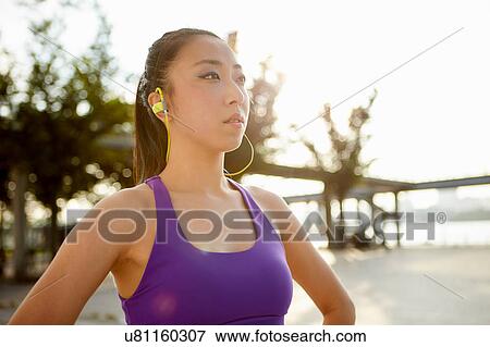 Stock Photo - Woman wearing spandex and earphones looking away. Fotosearch
