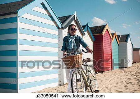 Woman with bicycle by beach huts View Large Photo Image Stock Image - Woman with bicycle by beach huts. Fotosearch