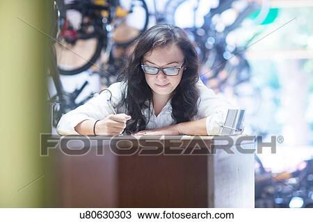 Woman working at counter in bicycle shop View Large Photo Image Stock Image - Woman working at counter in bicycle shop. Fotosearch