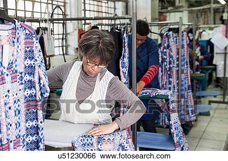 Worker ironing dress in garment factory View Large Photo Image Stock Photograph - Worker ironing dress in garment factory. Fotosearch