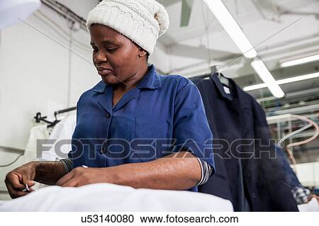 Stock Image - Worker ironing shirt in garment factory. Fotosearch