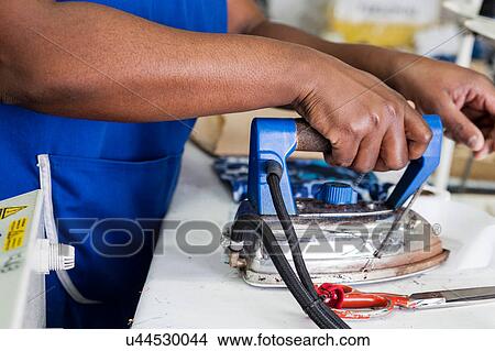 Worker using iron in garment factory View Large Photo Image Picture - Worker using iron in garment factory. Fotosearch