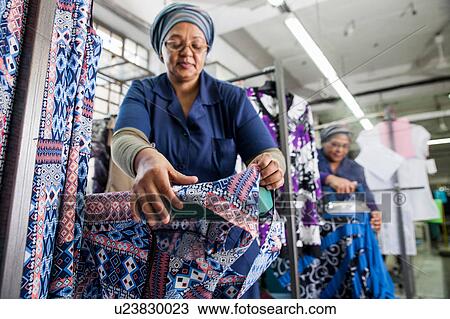 Stock Image - Workers ironing dress in garment factory. Fotosearch