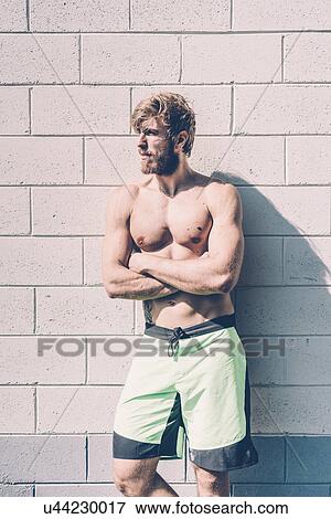 Young bare-chested male cross trainer leaning against wall outside gym View Large Photo Image Stock Photo - Young bare-chested male cross trainer leaning against wall outside gym. Fotosearch