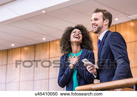 Young businessman and woman laughing on office balcony View Large Photo Image Stock Image - Young businessman and woman laughing on office balcony. Fotosearch