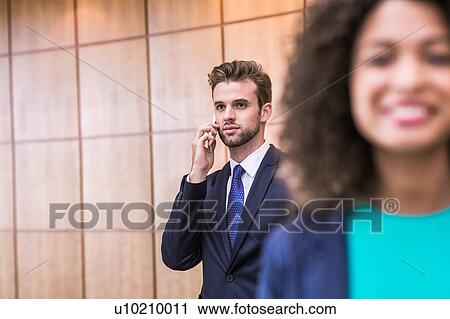 Young businessman talking on smartphone in office View Large Photo Image Stock Image - Young businessman talking on smartphone in office. Fotosearch