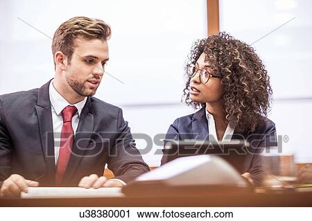 Young businesswoman and businessman brainstorming at boardroom table View Large Photo Image Stock Image - Young businesswoman and businessman brainstorming at boardroom table. Fotosearch