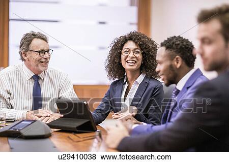 Stock Photo - Young businesswoman and three businessmen having discussion at boardroom table. Fotosearch