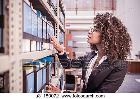 Young businesswoman searching office shelves View Large Photo Image Stock Image - Young businesswoman searching office shelves. Fotosearch