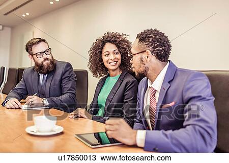Young businesswoman talking at conference table meeting with businessmen View Large Photo Image Stock Image - Young businesswoman talking at conference table meeting with businessmen. Fotosearch