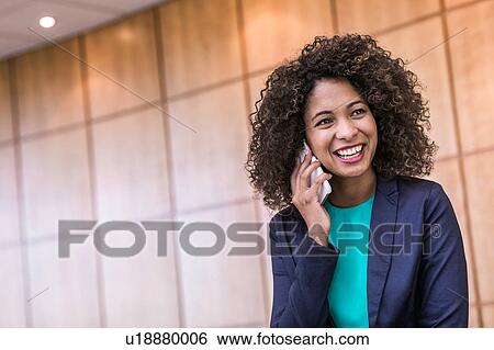 Young businesswoman talking on smartphone in office View Large Photo Image Stock Photograph - Young businesswoman talking on smartphone in office. Fotosearch