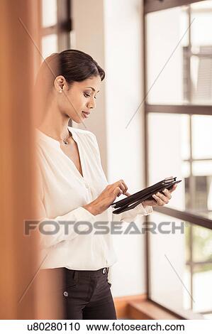 Young businesswoman using digital tablet in office View Large Photo Image Stock Image - Young businesswoman using digital tablet in office. Fotosearch