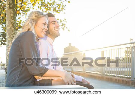 Stock Photo - Young couple sitting in sunlight at Regent's Canal, London, UK. Fotosearch