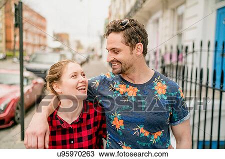 Stock Image - Young couple strolling along street, Kings Road, London, UK. Fotosearch