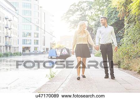 Young couple strolling hand in hand along Regent's Canal, London, UK View Large Photo Image Stock Photo - Young couple strolling hand in hand along Regent's Canal, London, UK. Fotosearch