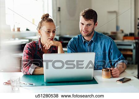Young craftsman and craftswoman looking at laptop in print studio workshop View Large Photo Image Stock Photo - Young craftsman and craftswoman looking at laptop in print studio workshop. Fotosearch