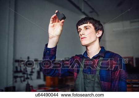 Picture - Young craftsman holding up letterpress letter in print workshop. Fotosearch