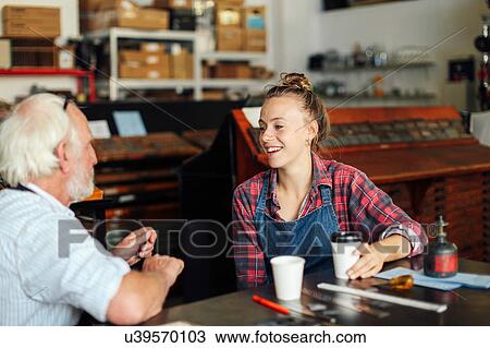 Young craftswoman drinking coffee, chatting and laughing with senior craftsman in book arts workshop View Large Photo Image Stock Image - Young craftswoman drinking coffee, chatting and laughing with senior craftsman in book arts workshop. Fotosearch