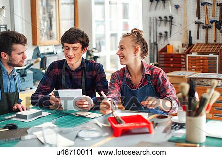 Young craftswoman holding brush and laughing and smiling with two young craftsmen in creative print studio View Large Photo Image Stock Image - Young craftswoman holding brush and laughing and smiling with two young craftsmen in creative print studio. Fotosearch