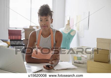 Stock Photo - Young fashion designer in home office. Fotosearch
