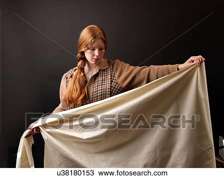 Stock Image - Young female designer inspecting rolled fabric. Fotosearch