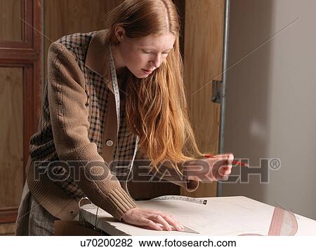 Young female fashion designer measuring dressmaker's pattern View Large Photo Image Stock Image - Young female fashion designer measuring dressmaker's pattern. Fotosearch