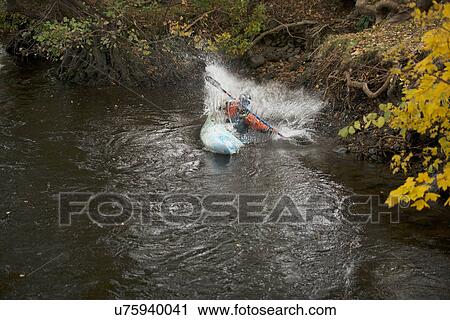 Stock Image - Young female kayaker splashing whilst paddling river Dee, Llangollen, North Wales. Fotosearch